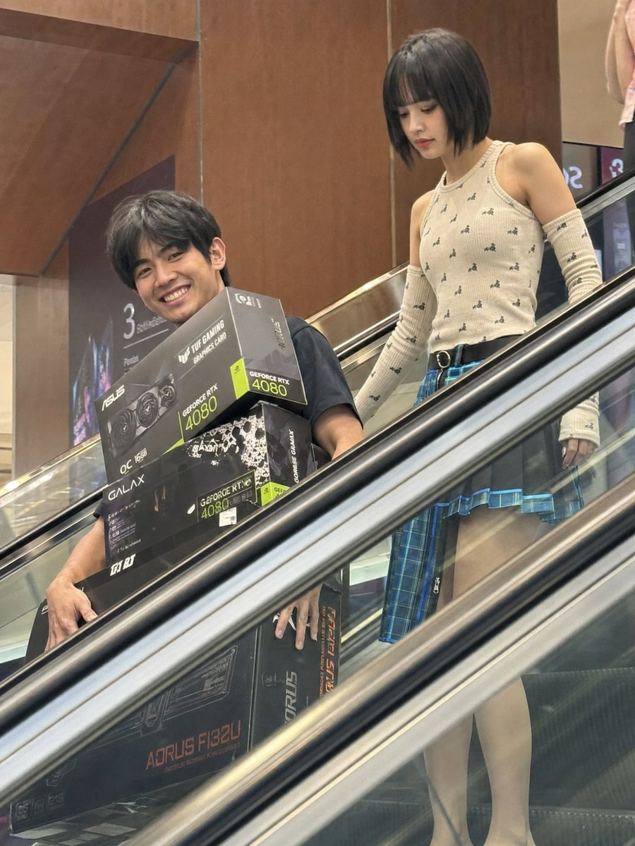 Candid Mall Shopping Snapshot Qwen Image 프롬프트 예시 변형 2: A realistic prompt for creating an imperfect, candid-style photo of two people on an escalator with electronics boxes,...