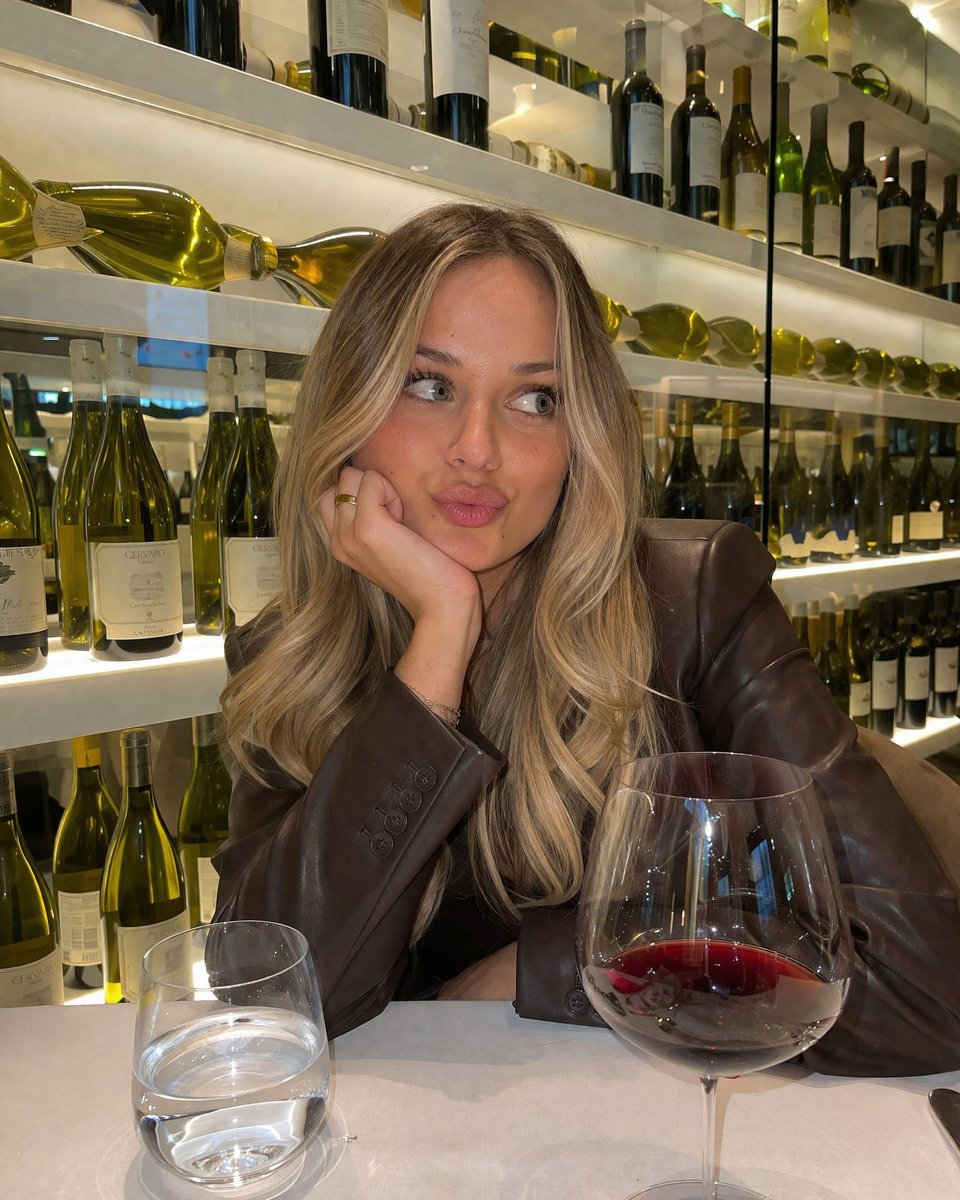 Casual Wine Bar Portrait Qwen Image prompt example: Generates a photorealistic, candid-style portrait of a person sitting at a restaurant table with drinks and a background of...