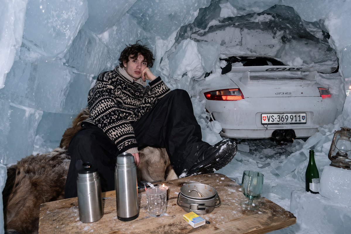 Surreal Ice Cave Flash Photography Qwen Image prompt example: Generates a realistic flash-photography style image of a person relaxing in an ice cave with a sports car embedded...