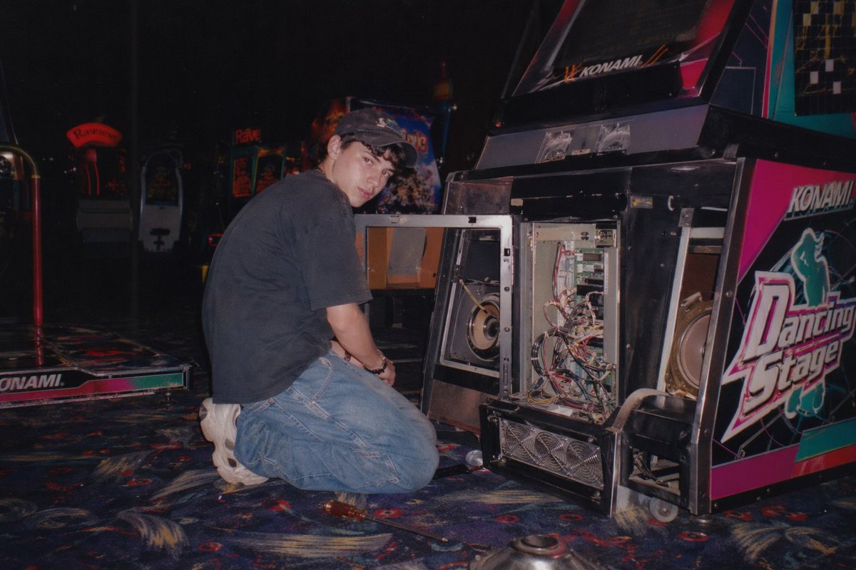 Vintage Arcade Repair Flash Photography GPT Image 2 prompt example: Generates a nostalgic, flash-lit photograph of someone repairing an open arcade cabinet in a dimly lit gaming...