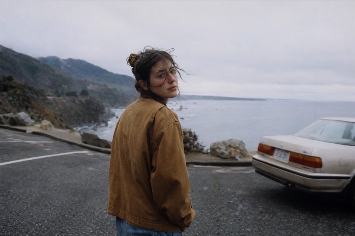 Moody Coastal Road Trip Portrait Qwen Image prompt example: This prompt generates a cinematic candid seaside roadside portrait with a parked vintage sedan, ideal for nostalgic...