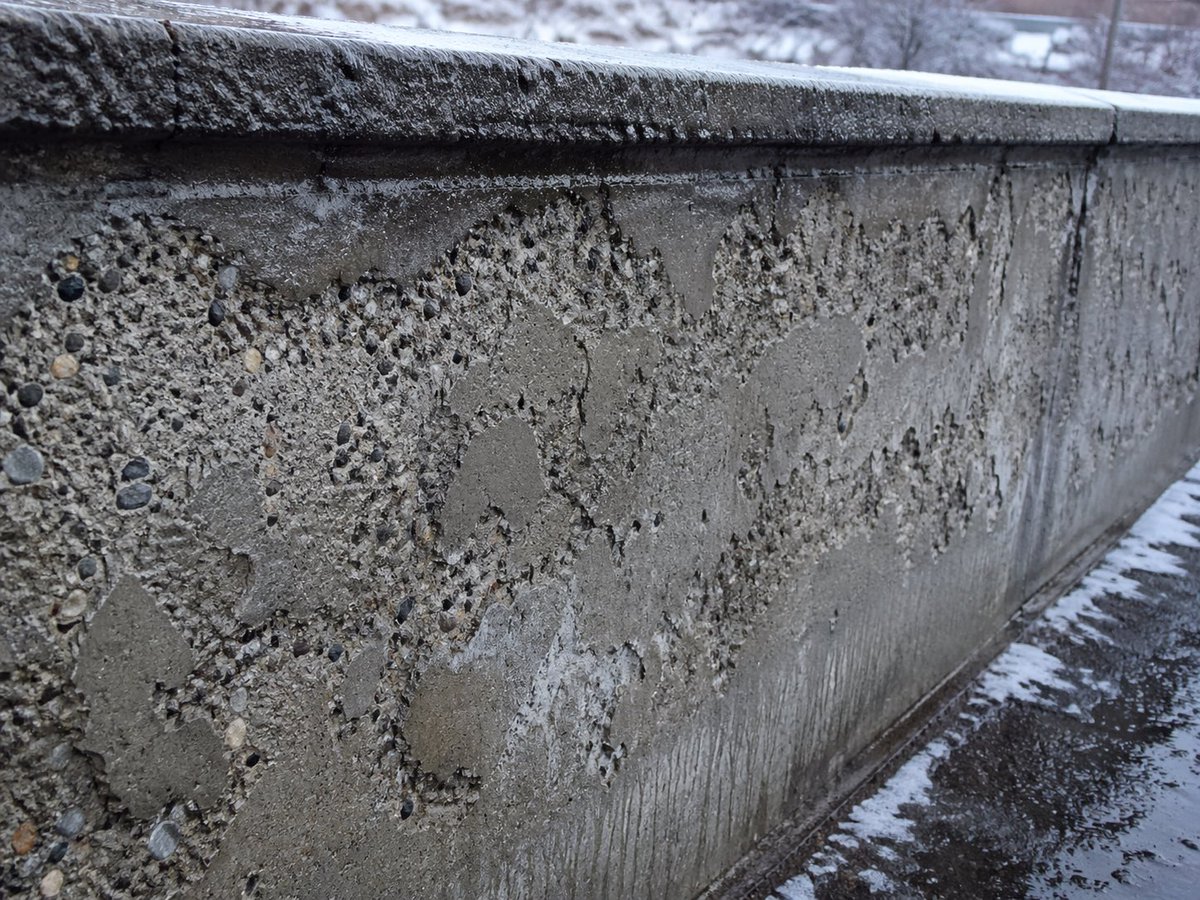 Winter Concrete Salt Damage Close-Up 的 Qwen Image 提示词示例图：A photorealistic inspection-style image of salt-damaged concrete in a snowy outdoor setting, useful for civil...