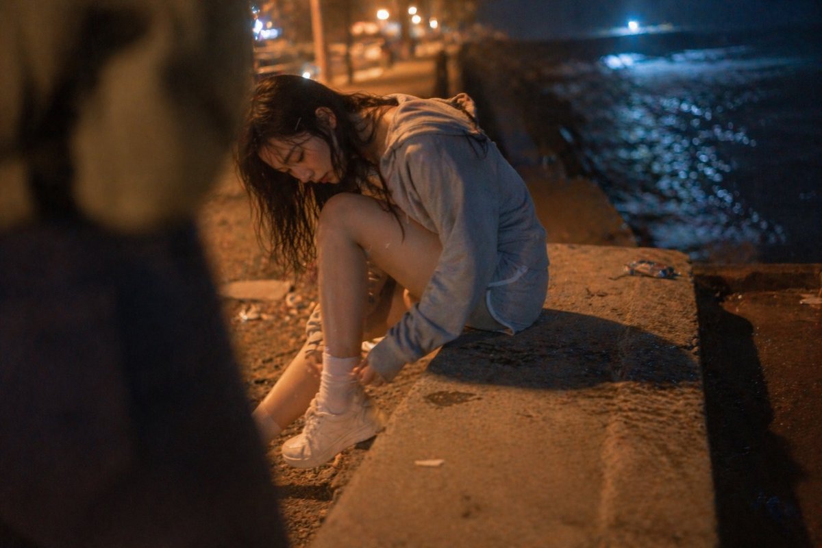 Cinematic Candid Night Seashore Portrait のQwen Imageプロンプト例: A highly detailed prompt for a cinematic, handheld-style shot of a woman at the beach at night with realistic skin...