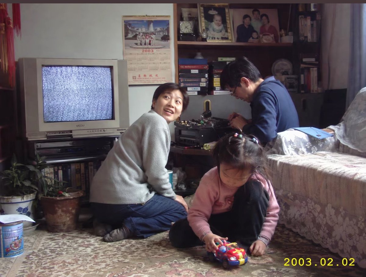 Early 2000s Family Living Room Photo 的 GPT Image 2 提示词示例图:A realistic nostalgic snapshot of a family in a cluttered early-2000s living room, useful for generating convincing...