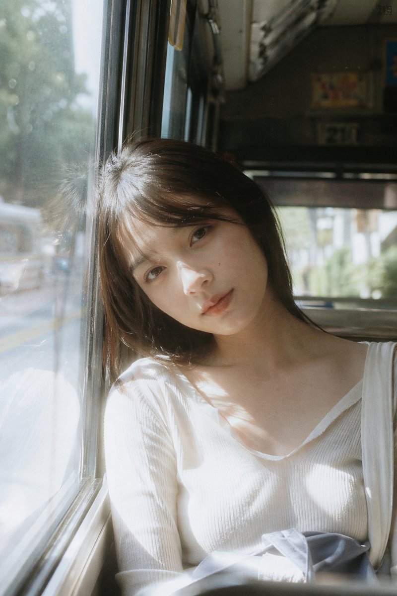 Bus Window Film Aesthetic のQwen Imageプロンプト例: A nostalgic prompt for a portrait on a bus seat using Japanese film aesthetics and natural light.