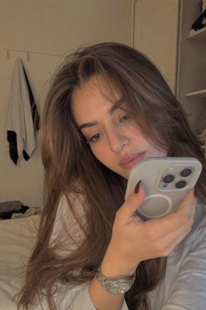 Realistic Bedroom Phone Recording Style 的 Qwen Image 提示词示例图:A prompt for a candid, low-fidelity style photo of a young woman in a bedroom, intended to look like a realistic phone...
