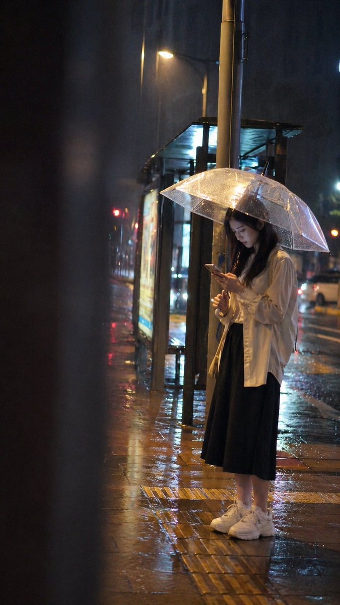 Cinematic rainy night bus stop prompt Qwen Image prompt example: A highly detailed atmospheric prompt for a realistic candid snapshot of a person at a bus stop during a rainy...