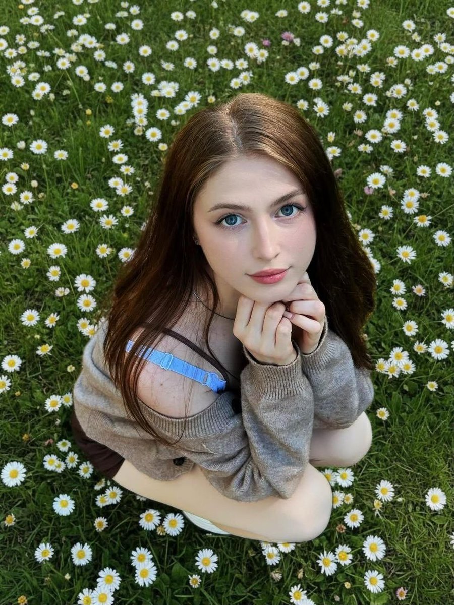 Girl in Daisy Meadow Portrait Qwen Image prompt example: A soft, whimsically-styled portrait prompt of a woman sitting in a field of daisies with natural daylight.