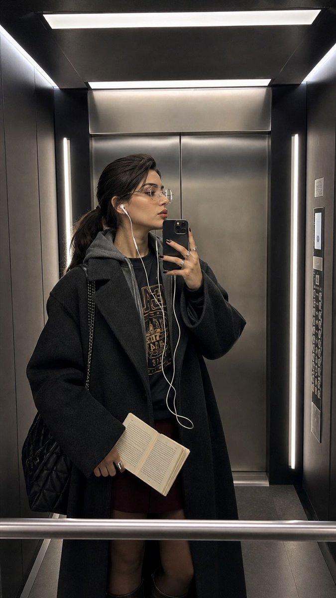 Modern Elevator Mirror Selfie 的 GPT Image 2 提示词示例图：A hyper-realistic iPhone mirror selfie prompt set in a dimly lit, sleek modern elevator with authentic skin textures and cool...